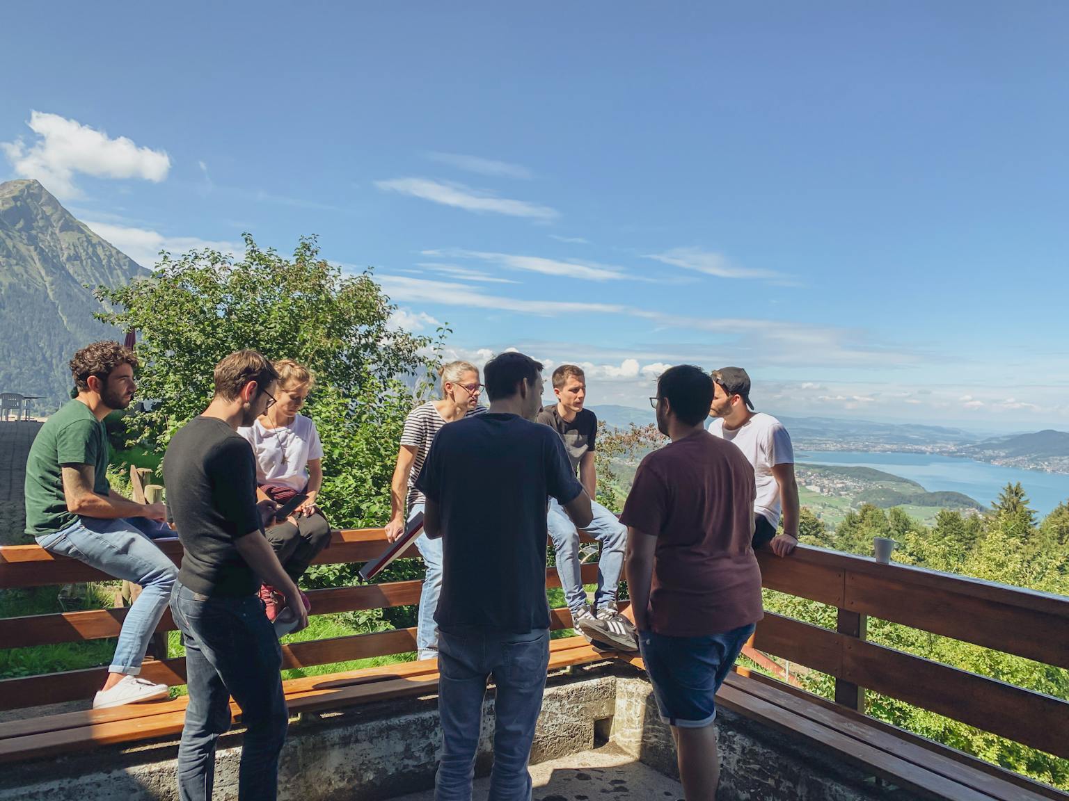 smartive Team sitzt auf einer Bank mit blauem Himmel und Thunersee im Hintergrund
